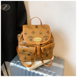 Detail shot of a brown monogram bucket backpack with gold hardware on a suitcase