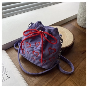 Détail du sac seau en velours côtelé violet avec broderie cœur et cordon de serrage