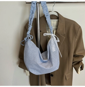 Blue and white striped hobo bag featuring a ruffled strap and a lace bow detail