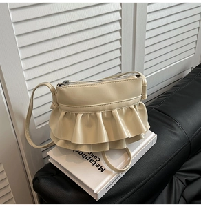 Detail of cream ballet-style crossbody bag with double layer ruffle trim and leather finish