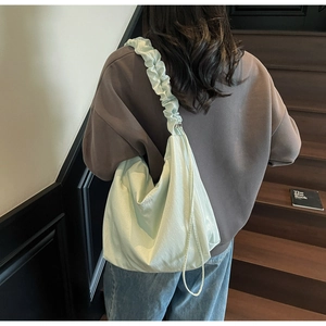 Detail of light green pleated shoulder bag with vibes embroidery and ruffled strap