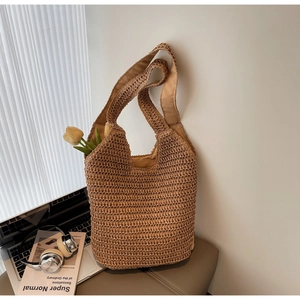 Detail of hand-woven straw tote bag showing large capacity with a yellow tulip inside