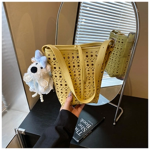 Détail du sac seau jaune ajouré avec motifs découpés au laser et breloque en peluche
