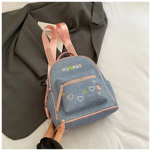 Detail of blue denim mini backpack with pink straps and cartoon embroidery on gray blazer