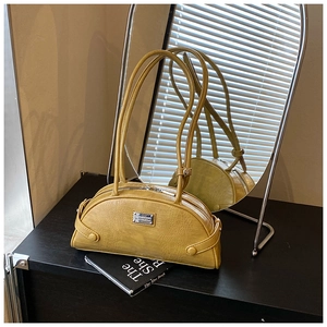 Detail of yellow crocodile pattern shoulder bag leaning on a book with mirror reflection