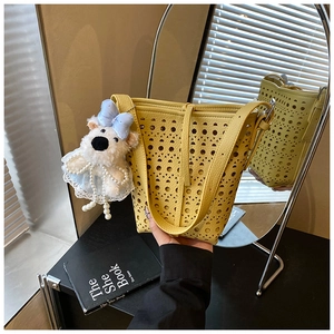 Détail du sac seau ajouré jaune avec une charmante peluche d'ours blanc décorative
