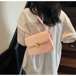 Detailed view of pink glossy crossbody bag with gold square buckle on a female model