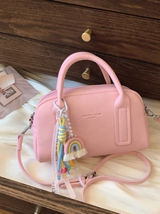 Pink Boston style leather handbag with rainbow pearl charm on vintage wooden background