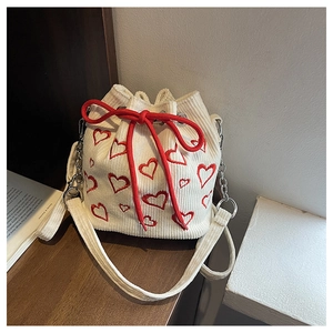 Détail du sac seau en velours côtelé blanc avec broderie de coeurs rouges et cordon