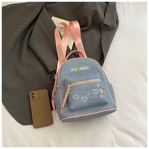 Close-up of blue denim backpack with pink straps and MUBAOB embroidery details