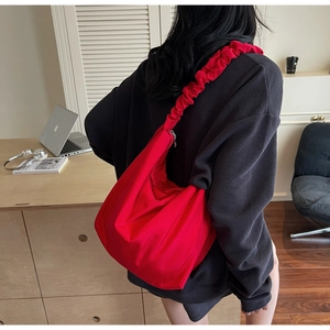 Detail of red canvas crossbody bag showing unique ruched shoulder strap and silver zipper