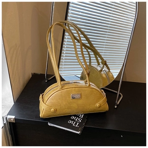 Detail of mustard yellow crocodile pattern handbag with silver metal plate on black surface
