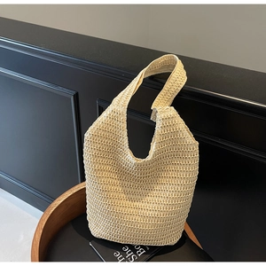 Detail of the woven hollow pattern and texture on a beige straw beach tote bag