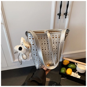 Détail du sac seau argenté ajouré au laser avec motif creux et breloque chiot
