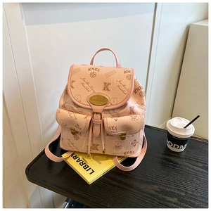 Pink mini backpack with bear monogram pattern on a yellow book in a lifestyle setting