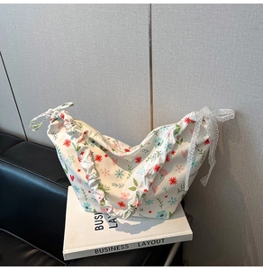 Detail of floral Oxford bag featuring pleated texture and large white lace bow decoration