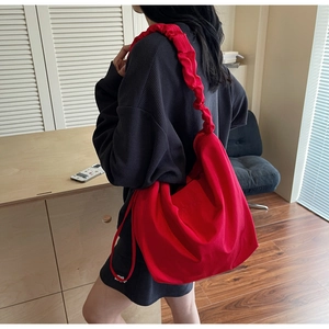 Detail of red canvas tote bag featuring stylish pleated shoulder strap and large capacity