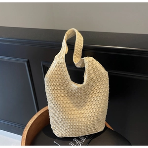 Detailed texture of beige woven straw tote bag with intricate grid pattern on dark background