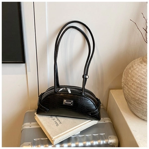 Close-up of black crocodile pattern baguette bag with silver hardware on vintage books