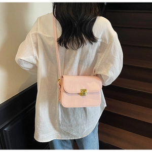 Close-up of pink patent leather crossbody bag featuring a golden square rotating lock