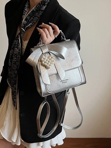 Metallic silver bow backpack with pearl heart charm and crinkled leather texture