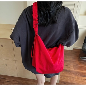Detail of red pleated canvas tote bag with a soft ruffled shoulder strap on female model