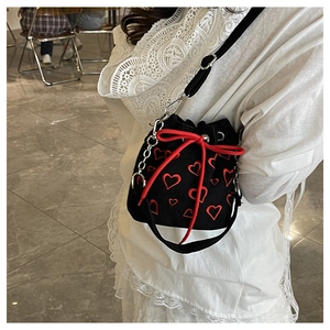 Détail du sac seau noir en velours avec broderies de cœurs rouges et cordon de serrage