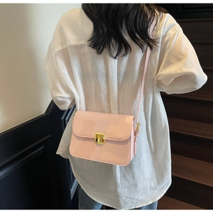 Detail of light pink patent leather shoulder bag with golden lock on female model