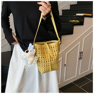 Détail du motif ajouré au laser sur sac seau jaune avec accessoire de charme chien en peluche