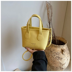 Vista dettagliata della pelle gialla a grana litchi su una mini borsa tote a mano