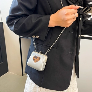 Silver heart-shaped mini bag with leopard print lining worn crossbody with bead chain