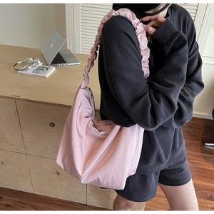Detail of pink pleated strap shoulder bag with happy vibe embroidery on model