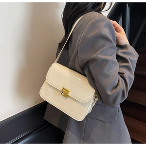 Detail of cream patent leather crossbody bag with premium gold metallic buckle closure