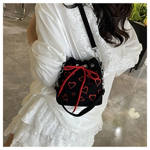 Détail du sac seau noir en velours avec broderies cœur rouge et nœud de serrage