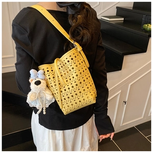 Détail du sac seau jaune ajouré avec un charm ours en peluche et chaîne de perles