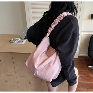 Pink pleated hobo bag detail with glossy fabric and cloud-style shoulder strap