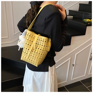 Détail du sac seau jaune découpé au laser avec motif géométrique ajouré sur un mannequin