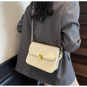 Detailed view of the creamy white crossbody bag with gold lock worn by a model