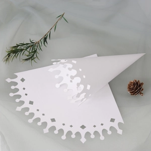 Detail of white laser-cut paper cone for wedding confetti with crown lace pattern