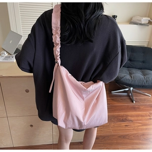 Detail of pink pleated canvas bag with embroidery and wide shoulder strap