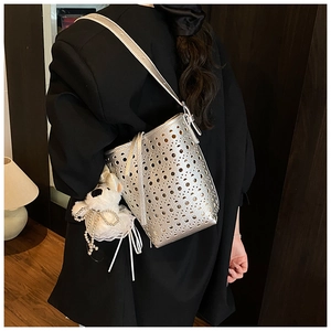 Sac seau argenté ajouré avec pendentif chiot porté à l'épaule dans un décor intérieur