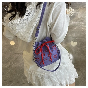 Détail du sac seau en velours côtelé violet avec broderie cœur rouge et cordon serrage