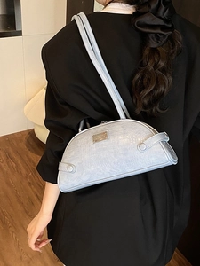 Light blue faux crocodile skin shoulder bag shown on model with minimalist design