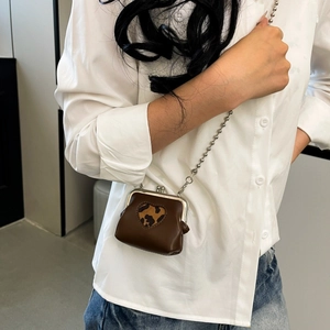 Close-up of a mini brown leather coin purse featuring a leopard print heart and silver chain