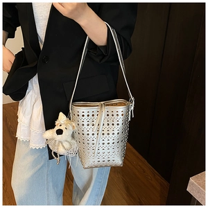 Détail du sac seau argenté ajouré avec un pendentif en peluche de chiot blanc mignon