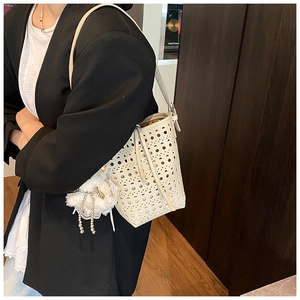 Détail du sac seau blanc crème avec motifs floraux découpés au laser et breloque en perles
