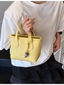 Mini borsa a secchiello gialla in pelle martellata con ciondolo in metallo e stile street