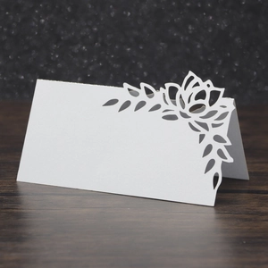 Close-up of white laser-cut floral place card with crystal accents on dark background