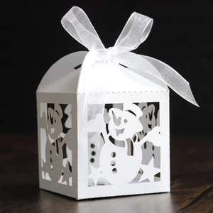 Detail of white laser-cut snowman gift box with elegant organza ribbon and star patterns