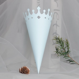 Close-up of light blue cone paper packaging with hollow crown pattern for wedding petals